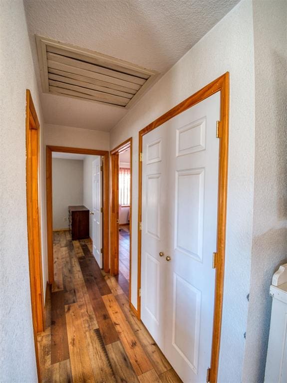 corridor with hardwood / wood-style floors and a textured ceiling