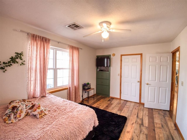 bedroom with ceiling fan, wood-type flooring, and a textured ceiling