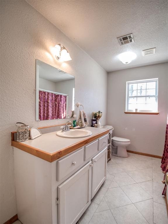 bathroom featuring tile patterned floors, vanity, toilet, and a textured ceiling