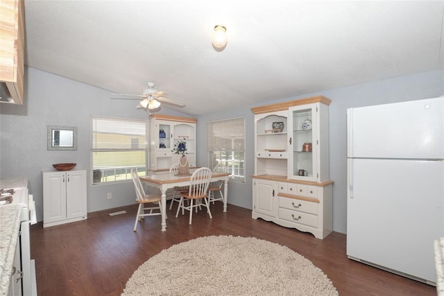 dining space featuring ceiling fan, dark hardwood / wood-style flooring, and vaulted ceiling