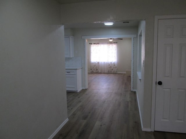 corridor featuring baseboards and wood finished floors