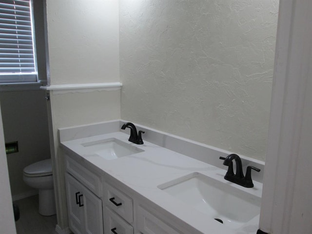 full bathroom featuring toilet, a sink, and a textured wall