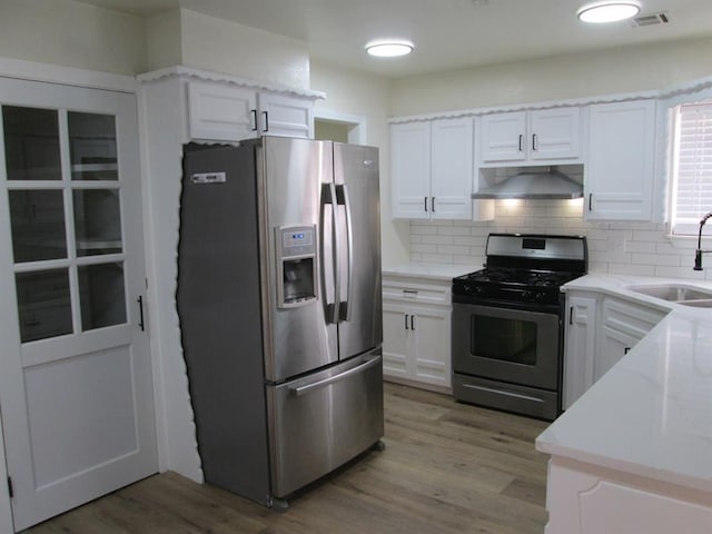 kitchen featuring stainless steel appliances, a sink, visible vents, light wood-type flooring, and range hood