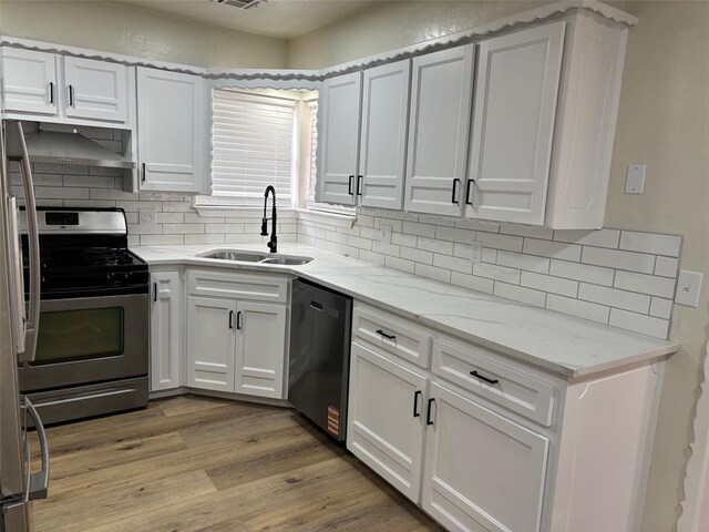 kitchen featuring appliances with stainless steel finishes, backsplash, light wood-type flooring, and a sink