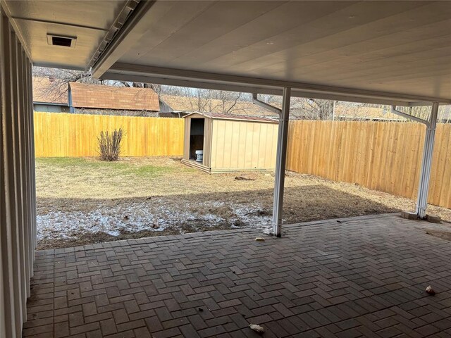 view of patio with a storage shed, a fenced backyard, visible vents, and an outbuilding