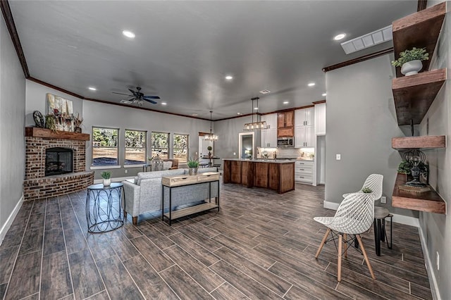 living room with ceiling fan, ornamental molding, and a brick fireplace