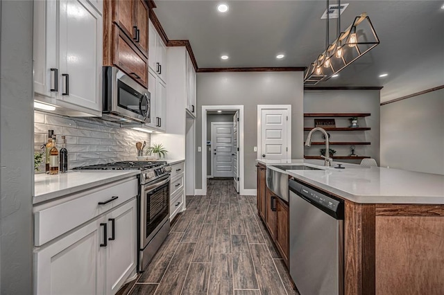 kitchen featuring appliances with stainless steel finishes, white cabinetry, hanging light fixtures, and ornamental molding