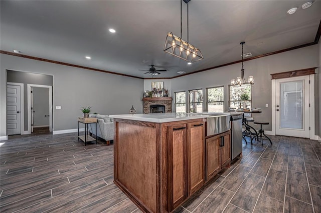 kitchen with sink, stainless steel dishwasher, pendant lighting, a center island with sink, and ceiling fan with notable chandelier