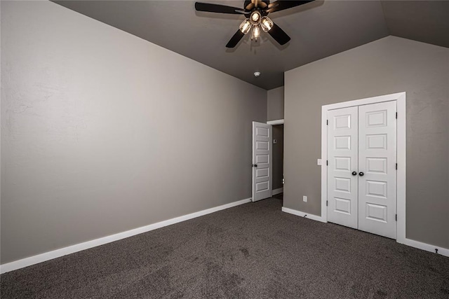 unfurnished bedroom with ceiling fan, a closet, dark carpet, and vaulted ceiling