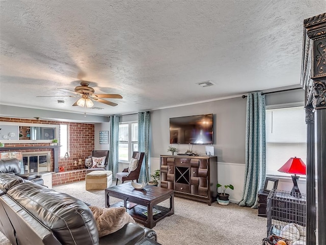 living room featuring a textured ceiling, a fireplace, ceiling fan, and light carpet