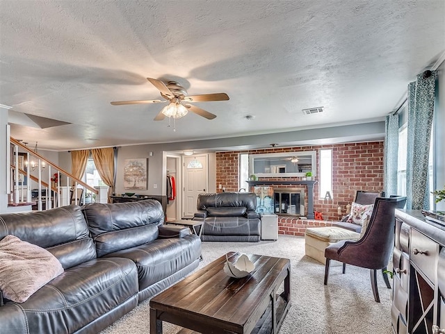 carpeted living room featuring ceiling fan with notable chandelier, a textured ceiling, and a brick fireplace