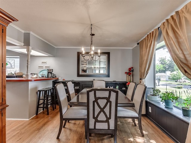 dining space with light wood-type flooring, crown molding, and a chandelier