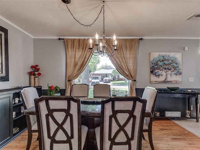 dining room featuring hardwood / wood-style flooring, crown molding, and a chandelier