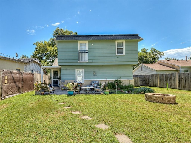 back of property featuring a lawn, a patio, and an outdoor fire pit