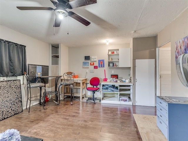 interior space featuring ceiling fan, white cabinetry, a textured ceiling, and light hardwood / wood-style flooring