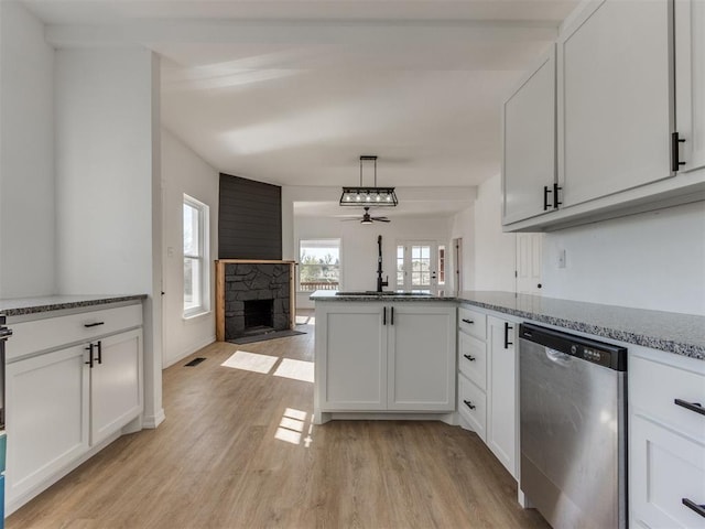 kitchen with white cabinets, dishwasher, ceiling fan, and a fireplace