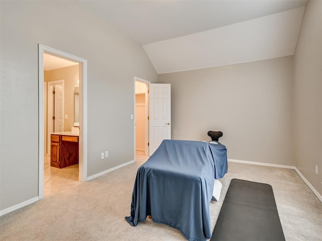 bedroom featuring ensuite bathroom, light carpet, and vaulted ceiling