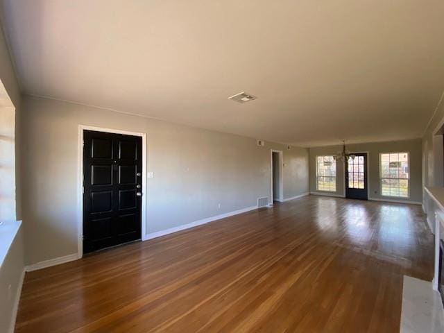 unfurnished living room with an inviting chandelier and hardwood / wood-style flooring