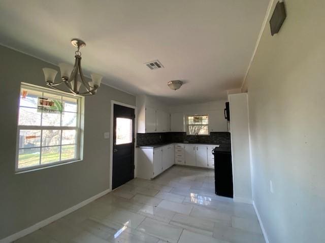 kitchen featuring an inviting chandelier, hanging light fixtures, decorative backsplash, light tile patterned flooring, and white cabinetry