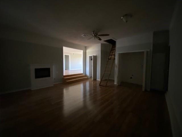 unfurnished living room with a fireplace, dark hardwood / wood-style floors, and ceiling fan