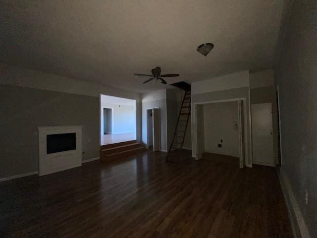 unfurnished living room featuring ceiling fan, a fireplace, and dark wood-type flooring