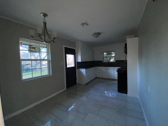 kitchen featuring white cabinets, decorative light fixtures, a chandelier, and decorative backsplash