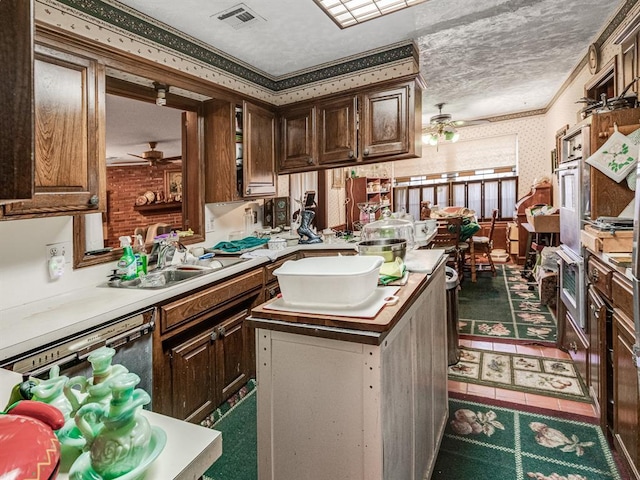 kitchen with sink, ceiling fan, ornamental molding, dishwashing machine, and a kitchen island