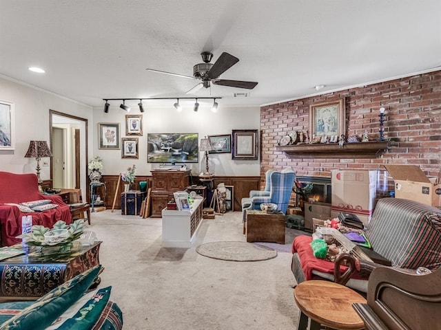 living room featuring rail lighting, a brick fireplace, light colored carpet, ceiling fan, and wood walls