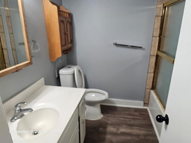 full bathroom with hardwood / wood-style floors, vanity, toilet, and shower / bath combination with glass door