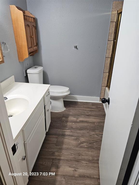 full bathroom with hardwood / wood-style floors, vanity, shower / bath combination, and toilet