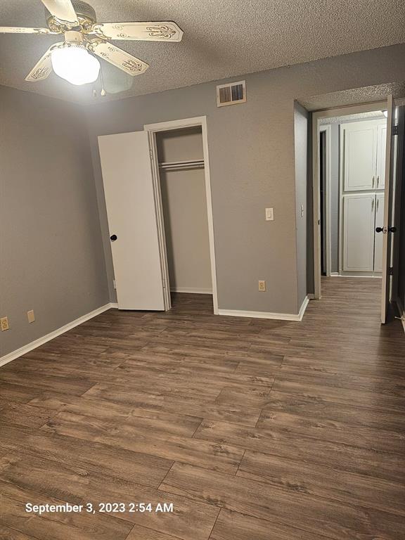 unfurnished bedroom featuring dark hardwood / wood-style flooring, ceiling fan, a closet, and a textured ceiling