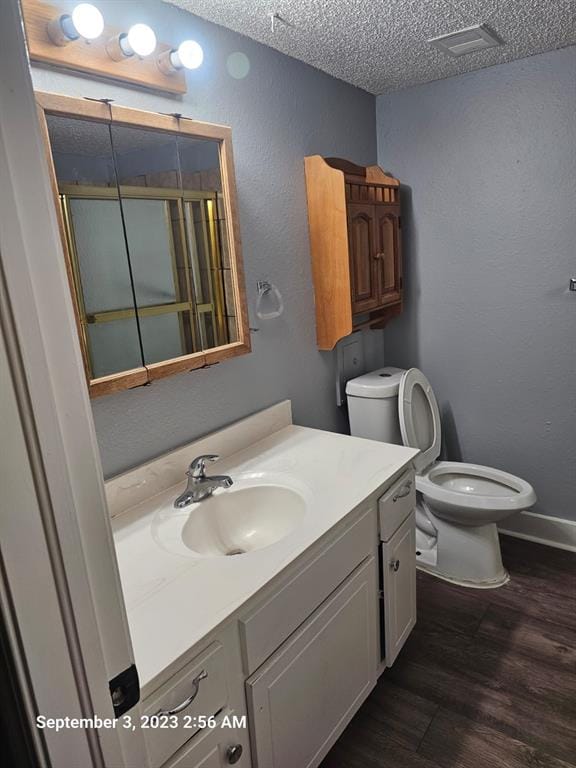 bathroom featuring vanity, wood-type flooring, a textured ceiling, and toilet