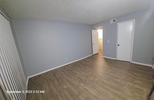 empty room featuring a textured ceiling and dark wood-type flooring