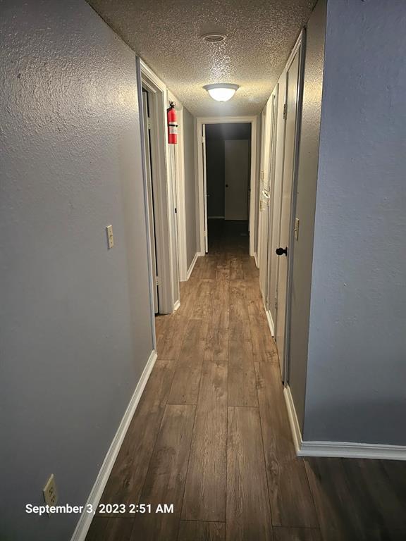 corridor with hardwood / wood-style floors and a textured ceiling