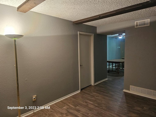 unfurnished room with beamed ceiling, ceiling fan, dark hardwood / wood-style flooring, and a textured ceiling