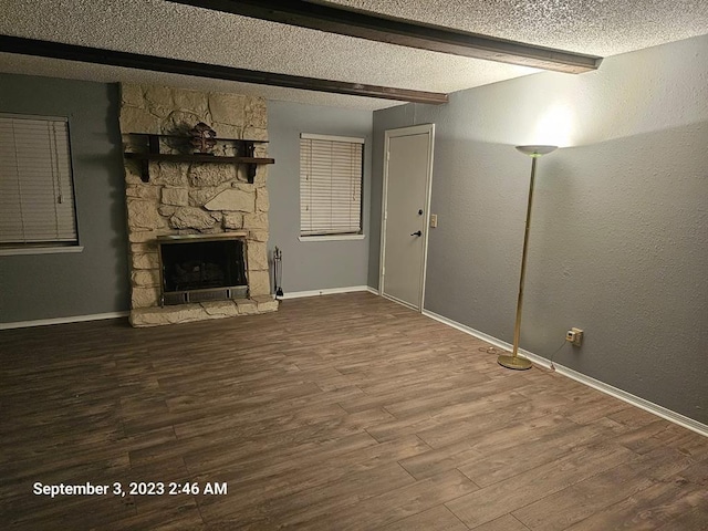 unfurnished living room with beamed ceiling, wood-type flooring, a textured ceiling, and a fireplace