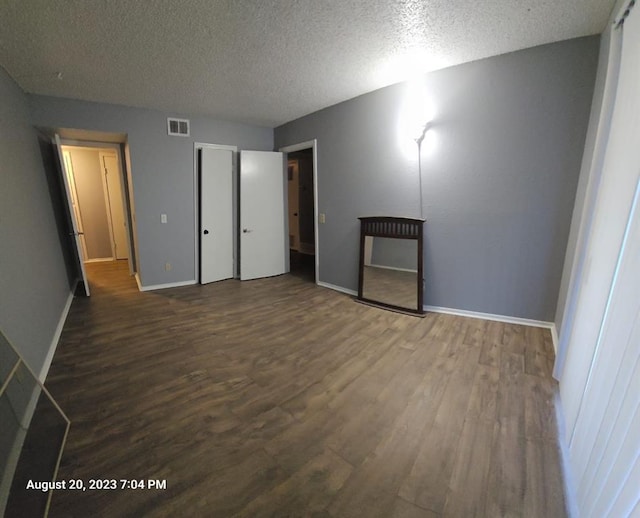 unfurnished bedroom with a textured ceiling and dark hardwood / wood-style flooring