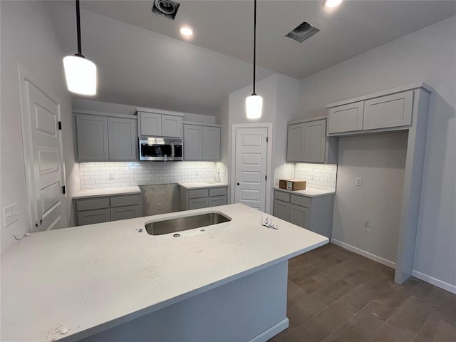 kitchen featuring sink, backsplash, gray cabinets, and decorative light fixtures