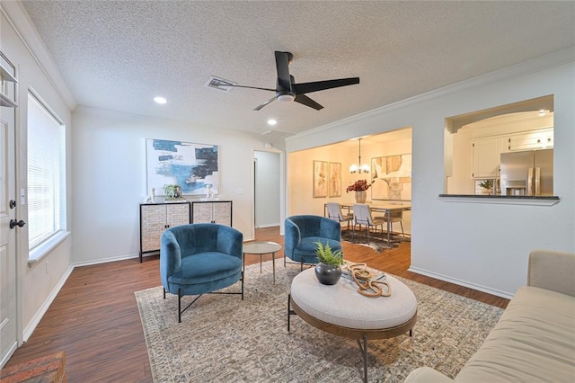 living room featuring a textured ceiling, dark hardwood / wood-style floors, ceiling fan with notable chandelier, and ornamental molding