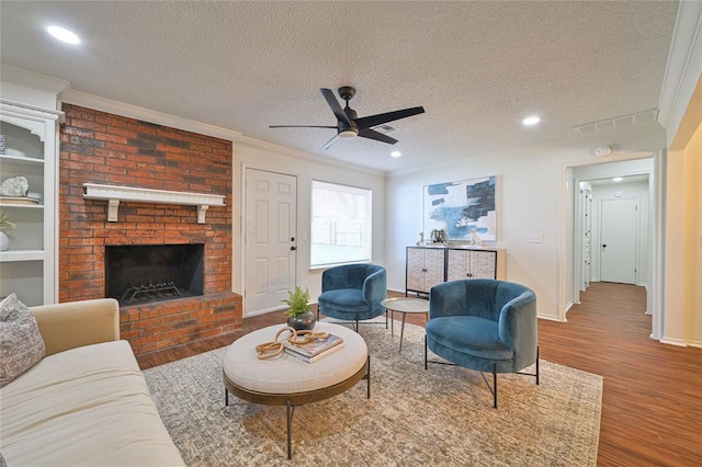 living room with a fireplace, ceiling fan, wood-type flooring, and a textured ceiling