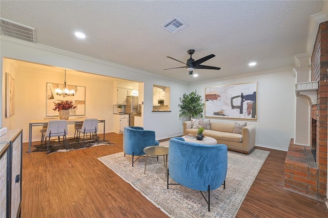 living room featuring ceiling fan with notable chandelier, dark hardwood / wood-style floors, ornamental molding, and a textured ceiling