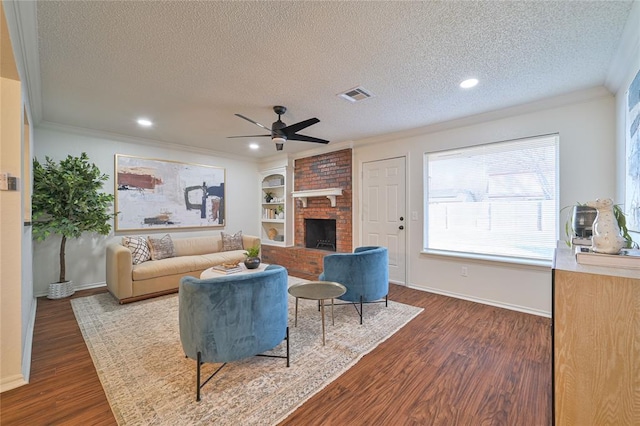 living room featuring built in features, dark hardwood / wood-style floors, a textured ceiling, and a brick fireplace