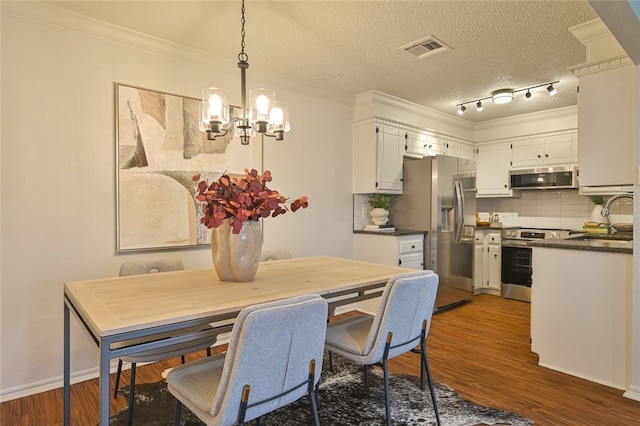 dining area with dark hardwood / wood-style floors, crown molding, a chandelier, and a textured ceiling