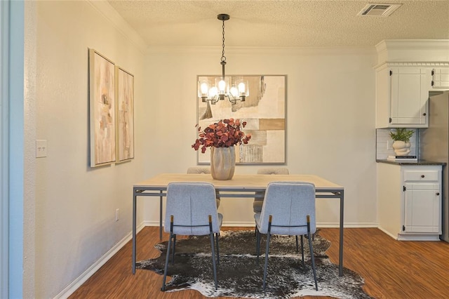 dining room with dark hardwood / wood-style flooring, a textured ceiling, an inviting chandelier, and crown molding