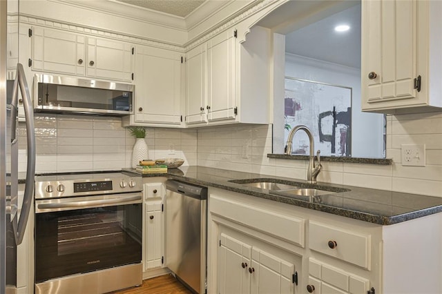 kitchen featuring backsplash, ornamental molding, stainless steel appliances, sink, and white cabinets