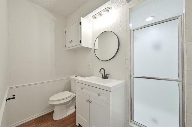 bathroom featuring vanity, a textured ceiling, a shower with door, wood-type flooring, and toilet