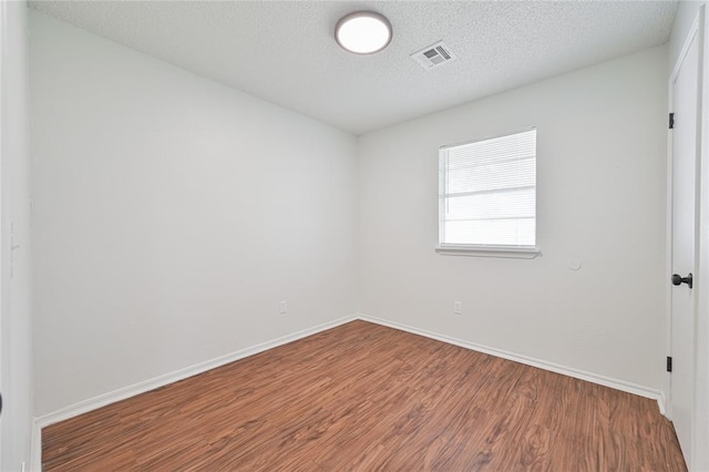 empty room featuring a textured ceiling and hardwood / wood-style flooring