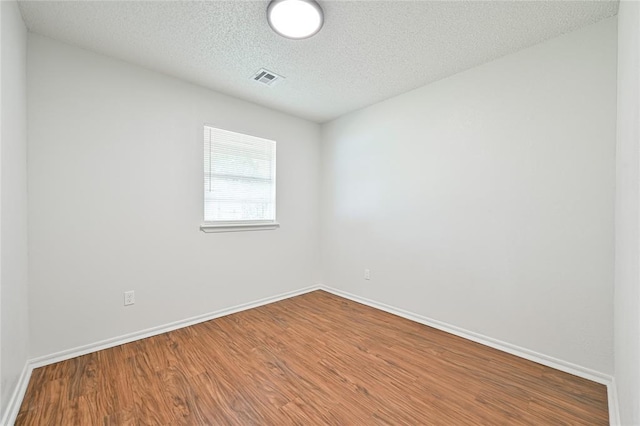 spare room featuring wood-type flooring and a textured ceiling