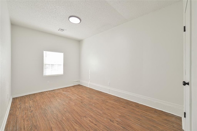 unfurnished room with hardwood / wood-style floors and a textured ceiling