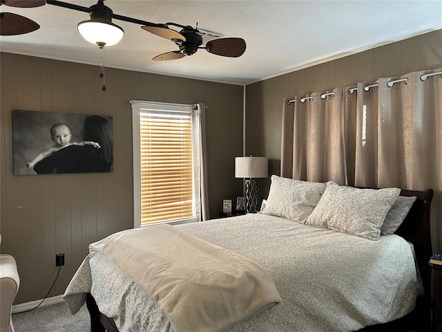 carpeted bedroom with ceiling fan and wood walls